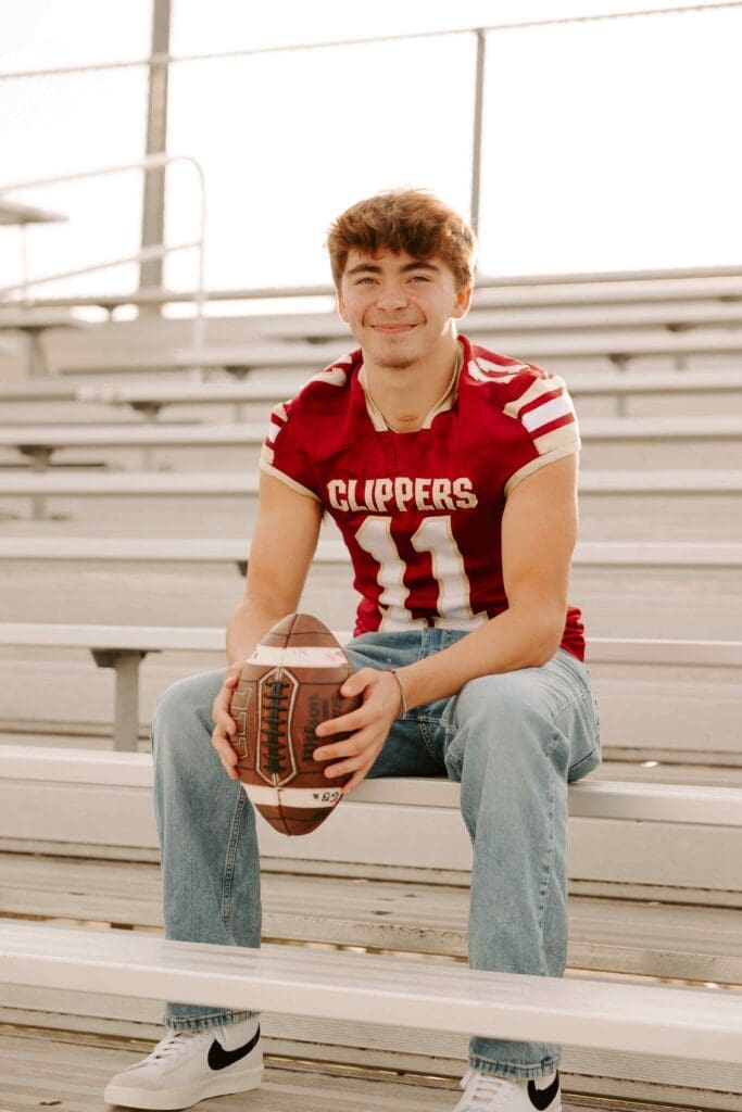 boy holding a football wearing a jersey