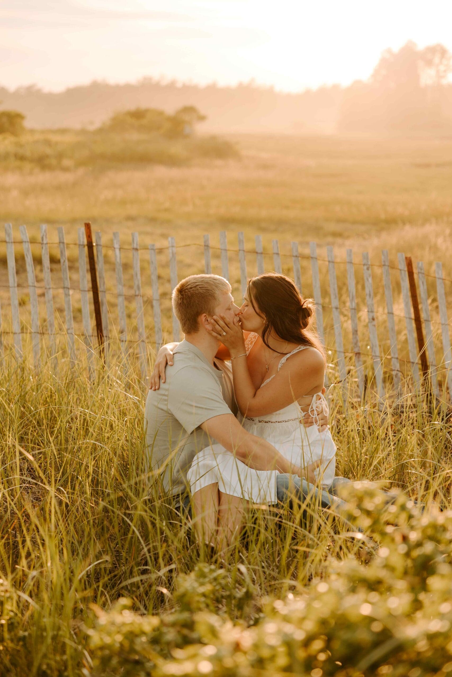 couple sitting in a field kissing